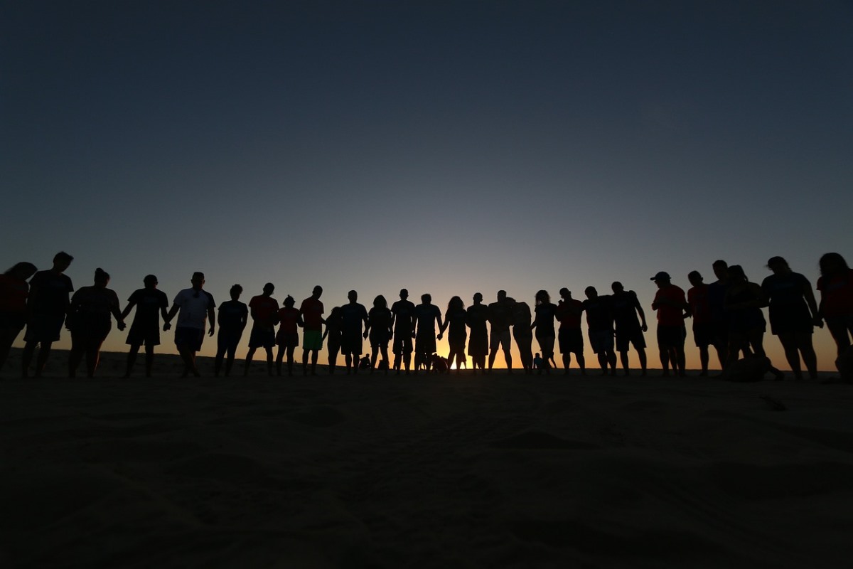 Grupa ludzi stojąca na plaży po zmierzchu