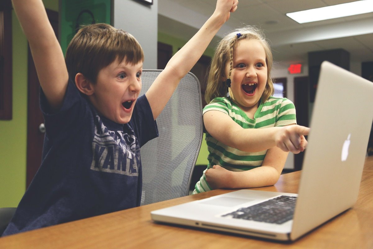 Dzieci cieszą się podczas zabawy/ nauki przy komputerze