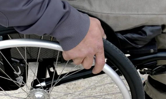 Osoba na wózku inwalidzkim trzymająca koło