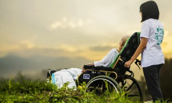 Opiekun z osobą z niepełnosprawnościami na spacerze na łące