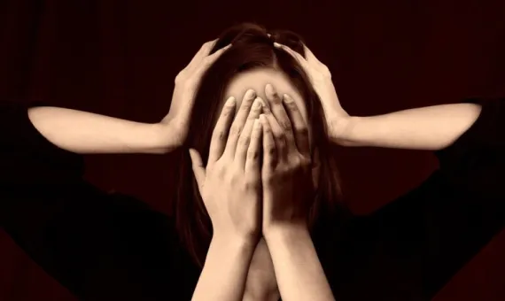 Kobieta zakrywa twarz dłońmi, ktoś trzyma dłonie na jej głowie