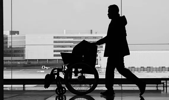 Mężczyzna prowadzi wózek dla osób z niepełnosprawnościami ruchowymi