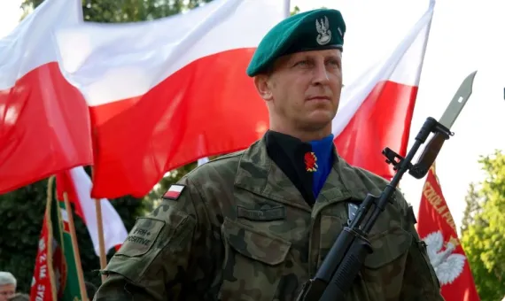 Polski żołnierz na tle flag Polski