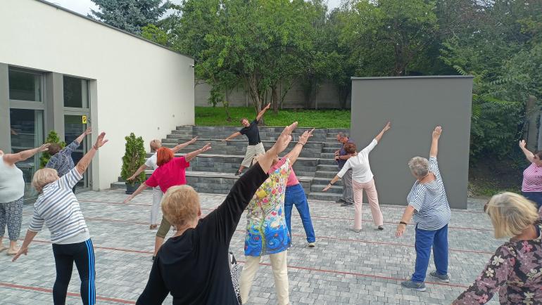Grupa ćwicząca Tai Chi na dziedzińcu Domu Integracji Międzypokoleniowej